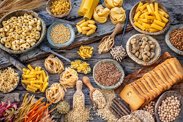 istock Different types of uncooked pasta on rustic wooden table, in the spoons, cutting board and bowls 2249274145
