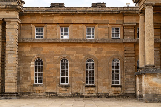 The building stands in quiet symmetry, pale windows framed within warm sandstone and age.