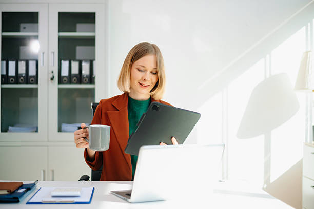 istock Professional woman on phone call in modern office, working on laptop. 2249275873
