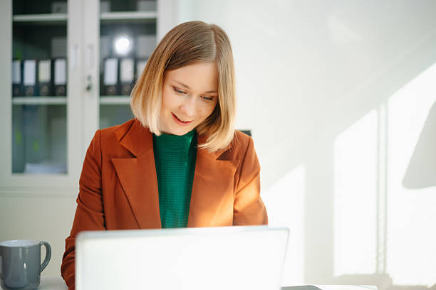 istock Focused business woman working on laptop in a bright modern office. Professional workspace, productivity, corporate job, technology, and career concept. 2249275879
