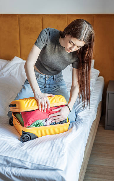 istock Young woman struggling with overstuffed suitcase on bed 2249276160