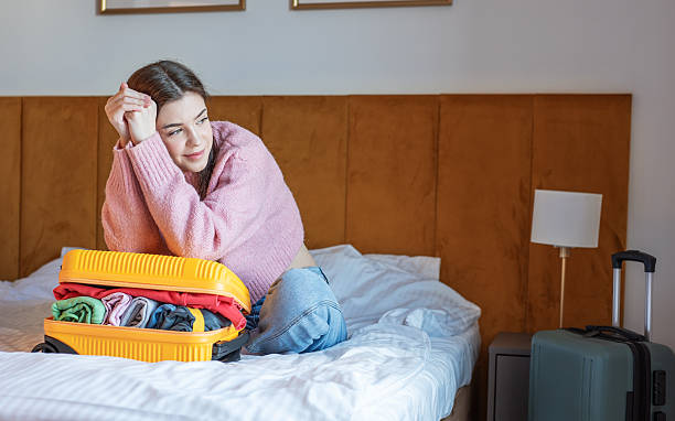 istock Woman dreaming about travel while packing suitcase on bed 2249276164