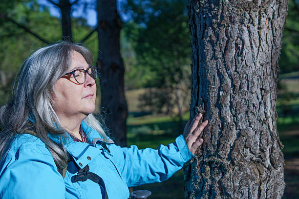istock Senior woman connecting with nature touching tree 2249276461