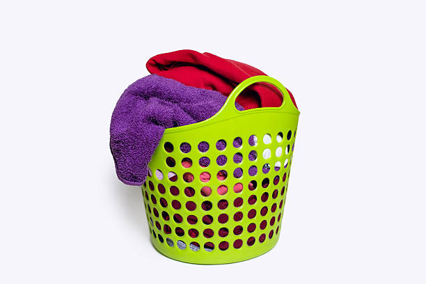 Man puts used dirty clothes in a dirty laundry basket. Collecting dirty clothes for laundry, standing in white minimalist bathroom. Household concept