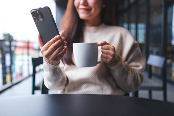 istock Portrait image of a woman holding and using mobile phone while drinking coffee in cafe 2249277753
