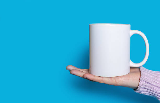 istock A woman's hand holds a white cup with a hot drink on a blue background 2249277782