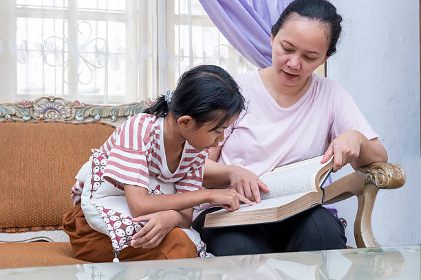 istock Woman and a child are sitting on a couch reading a book 2249278714