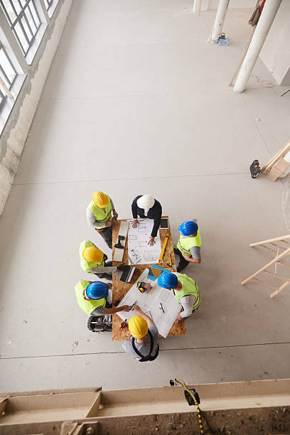 istock Above view of project manager and workers working on plans at construction site. 2249280475
