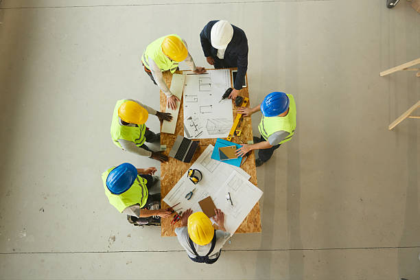 istock Above view of architect and manual workers working on plans at construction site. 2249280555