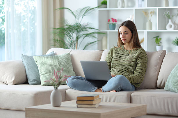 istock Serious woman in green using laptop sitting on a sofa 2249283822
