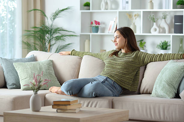 istock Woman in green relaxing looking away on a sofa 2249283862