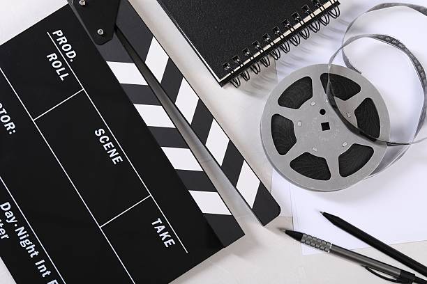 istock Movie clapper, film reel, notebook and pens on light table, flat lay 2249285143