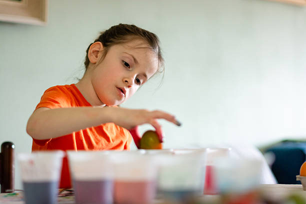 Girl concentrating on coloring Easter eggs with food dye, celebrating a spring holiday and family craft activity