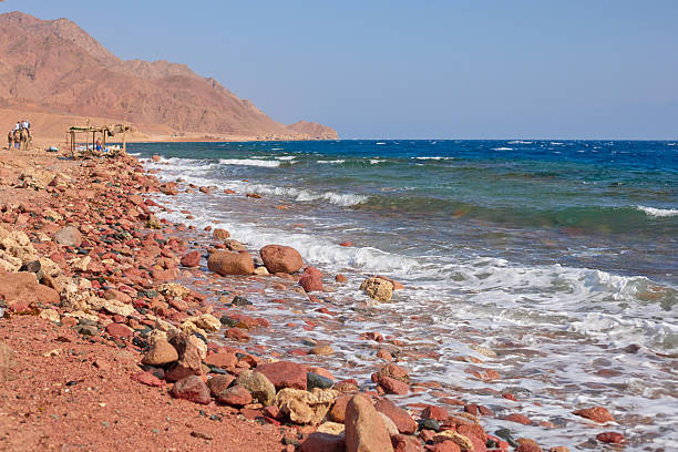 Beautiful shoreline featuring vibrant pebbles, clear blue water, and gentle waves creating a serene coastal atmosphere