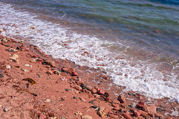 Scenic view of a rocky beach shoreline where gentle waves meet the sandy shore, showcasing vibrant textures and natural beauty