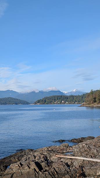 istock Coastal Landscape with rocky beach, Calm Ocean Waters, and Cloud-Covered Mountain Backdrop 2249285862