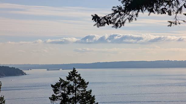 istock Tranquil Peaceful Ocean Inlet with Forested Shoreline, Horizon Vessels with Tree Silhouette and Partly Cloudy Sky 2249285886
