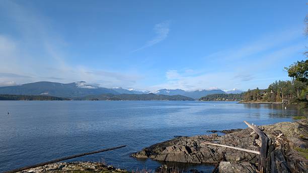 istock Coastal Landscape with rocky beach, Calm Ocean Waters, and Cloud-Covered Mountain Backdrop 2249285932