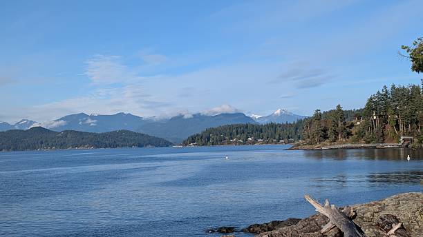 istock Coastal Landscape with rocky beach, Calm Ocean Waters, and Cloud-Covered Mountain Backdrop 2249286123