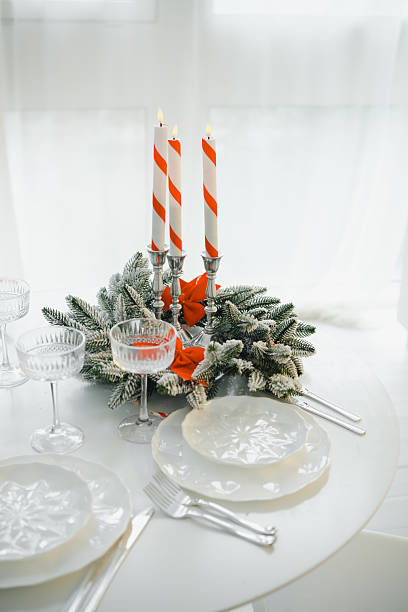 istock Festive table setting with striped candles and evergreen centerpiece decorated with bows. 2249287474