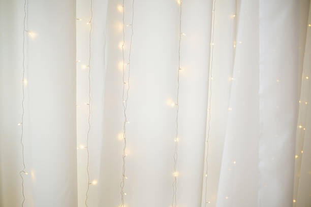 istock Soft white fabric curtains with gentle glowing fairy lights draped behind 2249288336