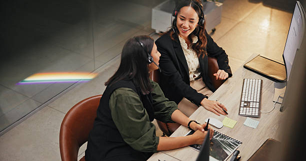 istock Customer support, women and talking with headset, office and working late with new system and above. Call center, supervisor and people with tech for software troubleshooting, training and night 2249289071