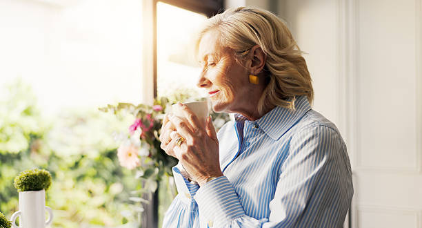 istock Coffee, dreaming and senior woman by window in home for reflection, memory or thinking in morning. Cappuccino, nostalgia and elderly female person drinking warm beverage for retirement in apartment. 2249290485