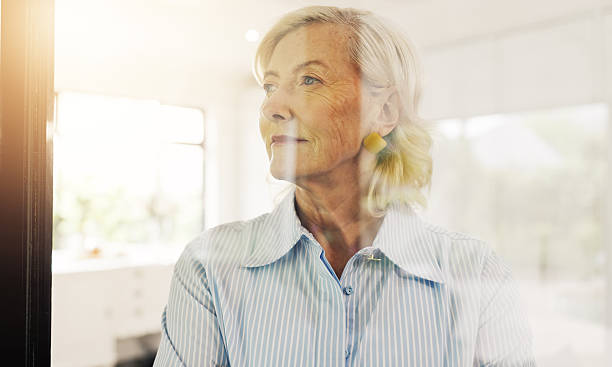istock Senior, woman and thinking with window for reflection, ambition or nostalgia in home. Elderly, female person or thoughtful with dream, idea or reminisce for perception, insight or vision in house 2249290532