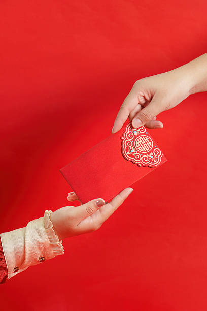 istock Lunar New Year Tradition. Hands exchanging red envelope with blessings. 2249290544
