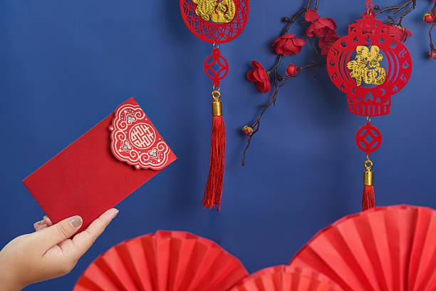 istock Lunar New Year celebration. Hand holding red envelope with traditional decorations. 2249290665