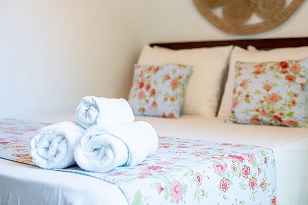 istock Neatly Rolled Towels on Floral Bedspread 2249293181