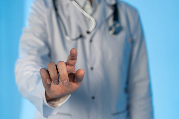 istock Man doctor in white coat with stethoscope touching transparent interface screen with finger gesture on blue background, representing healthcare concept. 2249293229