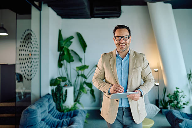 istock Smiling businessman holding a digital tablet in a modern office, representing entrepreneurial success and technology 2249293264