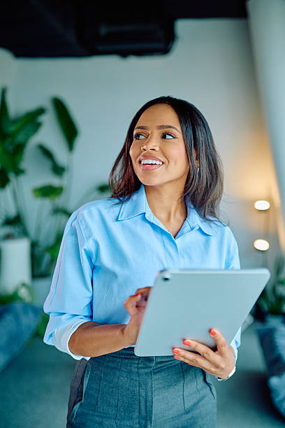 istock Black businesswoman smiling, using digital tablet in modern office, finding inspiration, planning future success 2249293369