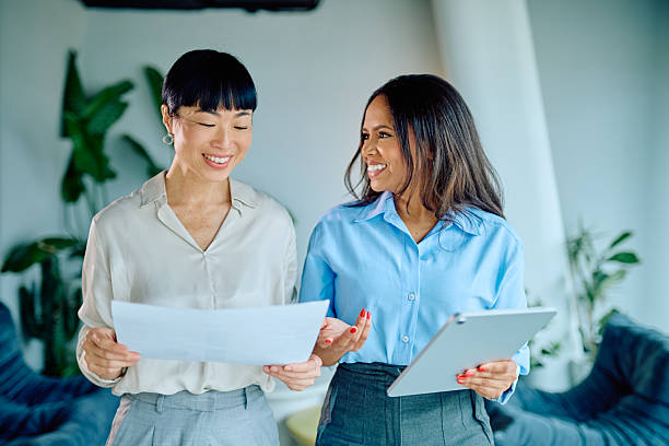 istock Diverse businesswomen collaborating on a project, discussing documents and digital information in a modern office environment 2249293474
