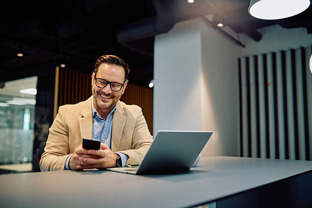 istock Happy businessman using smartphone and laptop for remote work or online communication in modern office 2249295722