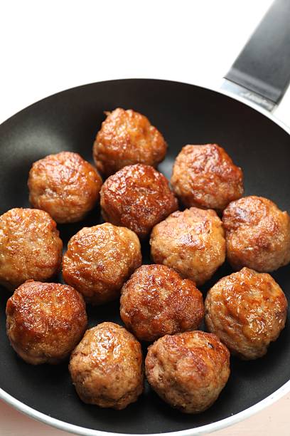 Tasty meatballs in frying pan on white table, closeup
