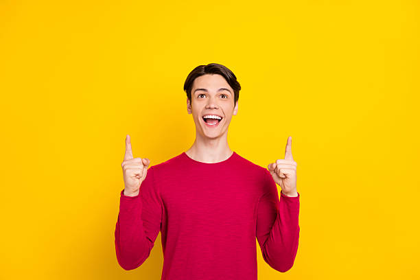 istock Photo of attractive impressed young guy neck dressed red pullover smiling pointing fingers up empty space isolated yellow color background 2249298910