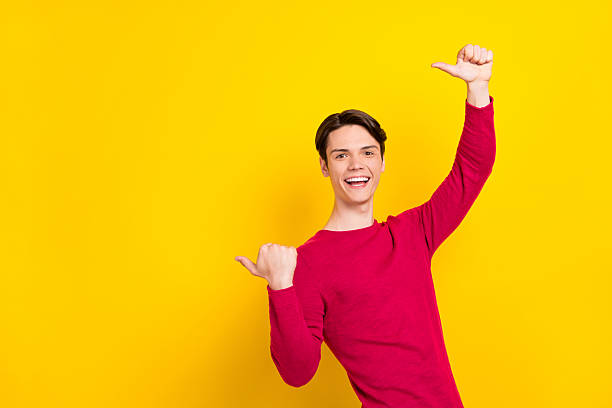 istock Photo of impressed funny young gentleman wear red pullover pointing thumbs up empty space smiling isolated yellow color background 2249298923
