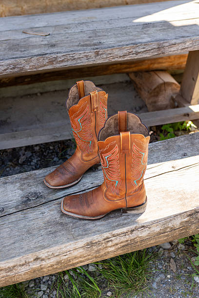 istock Leather cowboy boots on rustic wooden bench outdoors 2249300444