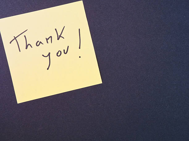 istock Thank You Sticky Note on Dark Background - Bright yellow sticky note with 'Thank You!' message in black script on a dark textured background. Ideal for expressing gratitude and appreciation. 2249300611