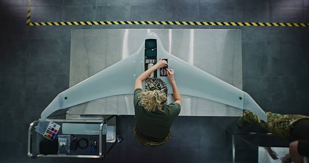 femme en uniforme de camouflage travaillant sur un drone de nouvelle génération - industrie aérospatiale photos et images de collection