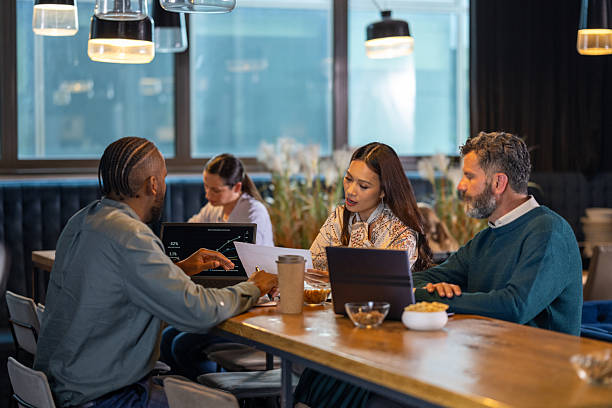 istock Diverse Business Executives Collaborating Energetically Over Laptops and Drinks in Office Setting 2249300663