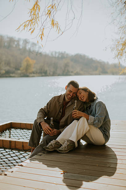 istock Couple enjoying a sunny afternoon by the lake while sipping drinks and sharing laughter 2249302423