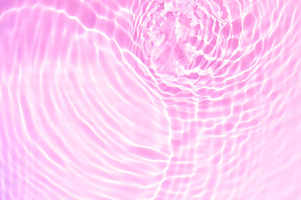 istock Pink water bubbles on the surface ripples. Defocus blurred transparent pink colored clear calm water surface texture with splash and bubbles. Water waves with shining pattern texture background 2249302494