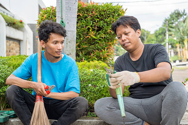 istock Two Indonesian southeast asian gardeners men sitting and resting while talking after doing some gardening in the backyard. Gardening work 2249303154