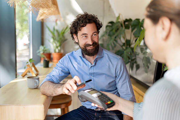 istock Smiling businessman paying his bill with smart phone at cafe 2249305963