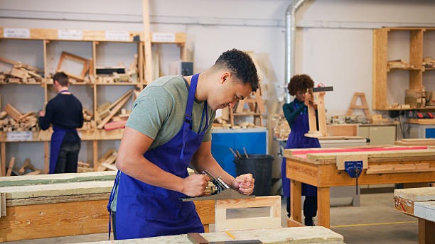istock Male Student Studying For Carpentry Apprenticeship At College Using Wood Plane 2249306314