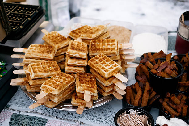Stack of Belgian Waffles on Sticks Displayed at Outdoor Street Food Market in Winter