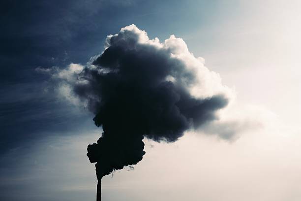 A dramatic photograph of thick dark smoke rising from an industrial chimney against a bright sky. The strong contrast highlights environmental issues such as air pollution, climate impact, and industrial emissions. Suitable for topics related to ecology, environmental protection, industrial development, global warming, and atmospheric pollution.